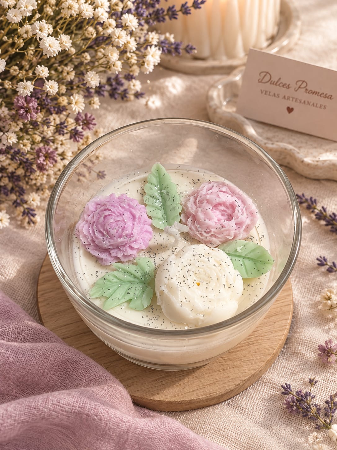 Vela Encanto Floral en cuenco de cristal con flores de cera rosa, lila y crema y hojas verdes